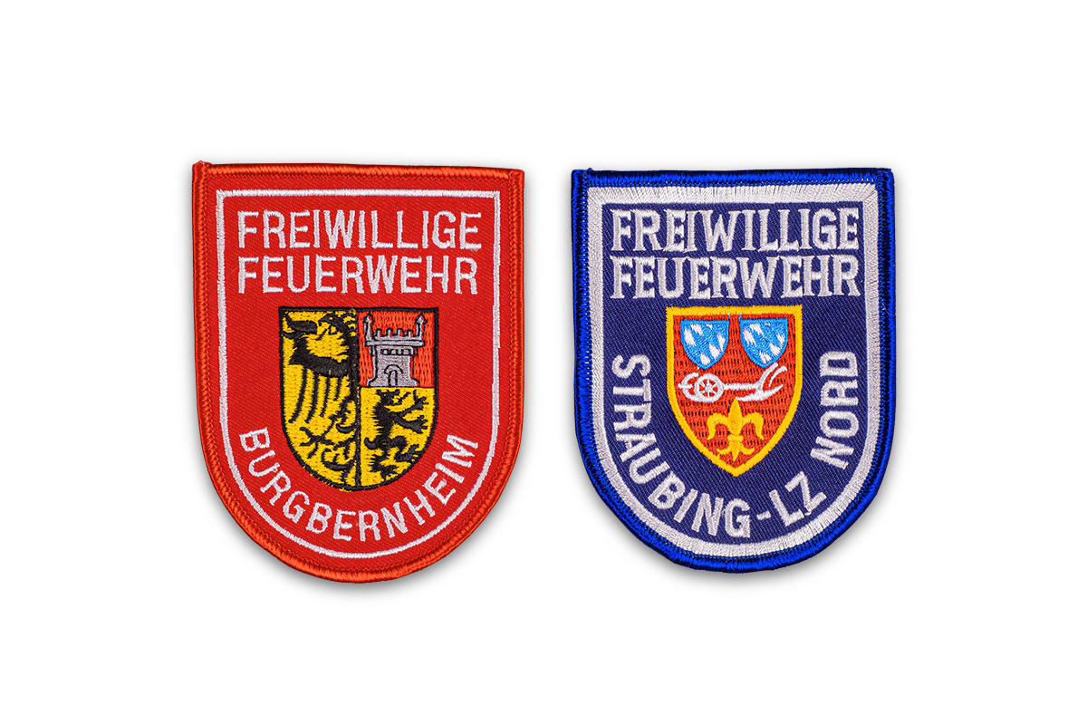 Rotes Stickabzeichen mit Wappen und Aufschrift FFW Burgbernheim sowie blaues Stickabzeichen mit Wappen und Aufschrift FFW Straubing-LZ Nord